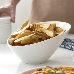 White bowl filled with potato wedges on a table.