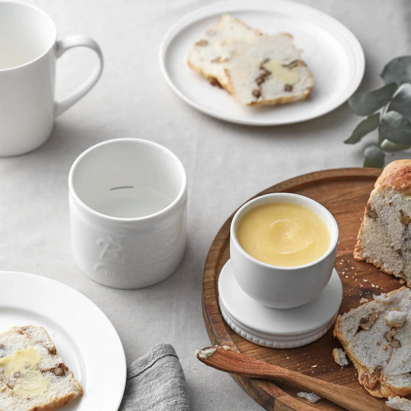 White ceramic cups on a table with bread and butter