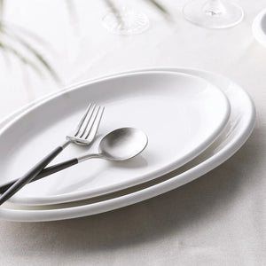 White ceramic plates with silver cutlery on a light gray surface