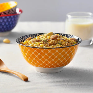 Orange bowl with cereal and nuts on a light gray surface
