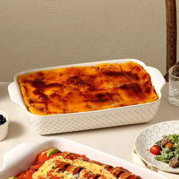 Rectangular stoneware baking dish with textured side and gold rim on a white background