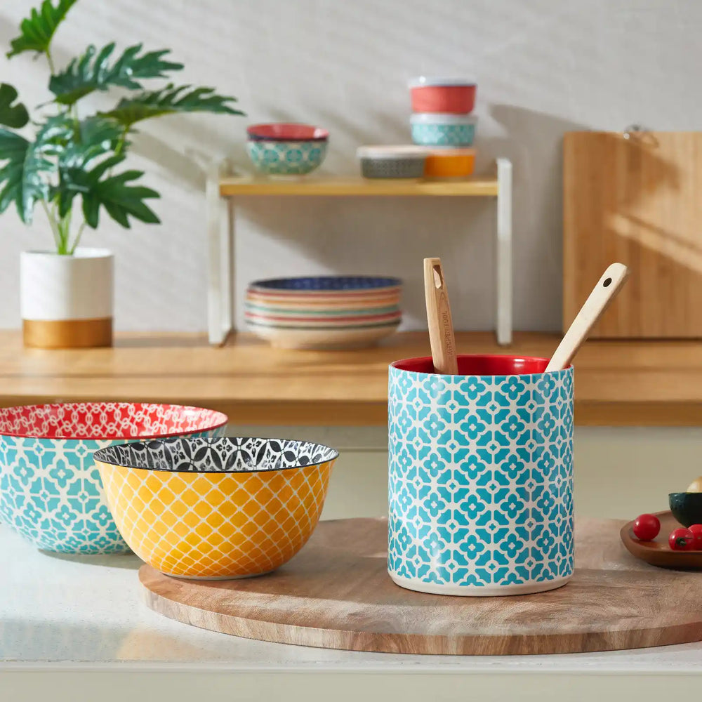 Cylindrical utensil holder with blue floral pattern and red interior on a white background