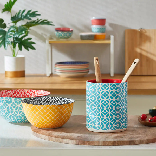 Colorful patterned bowls and a ceramic utensil holder on a kitchen counter.