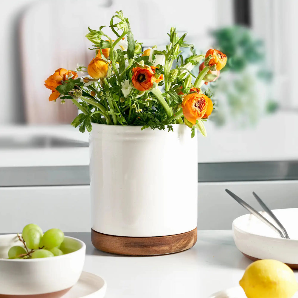 Ceramic rotating utensil holder with wooden base on a white background