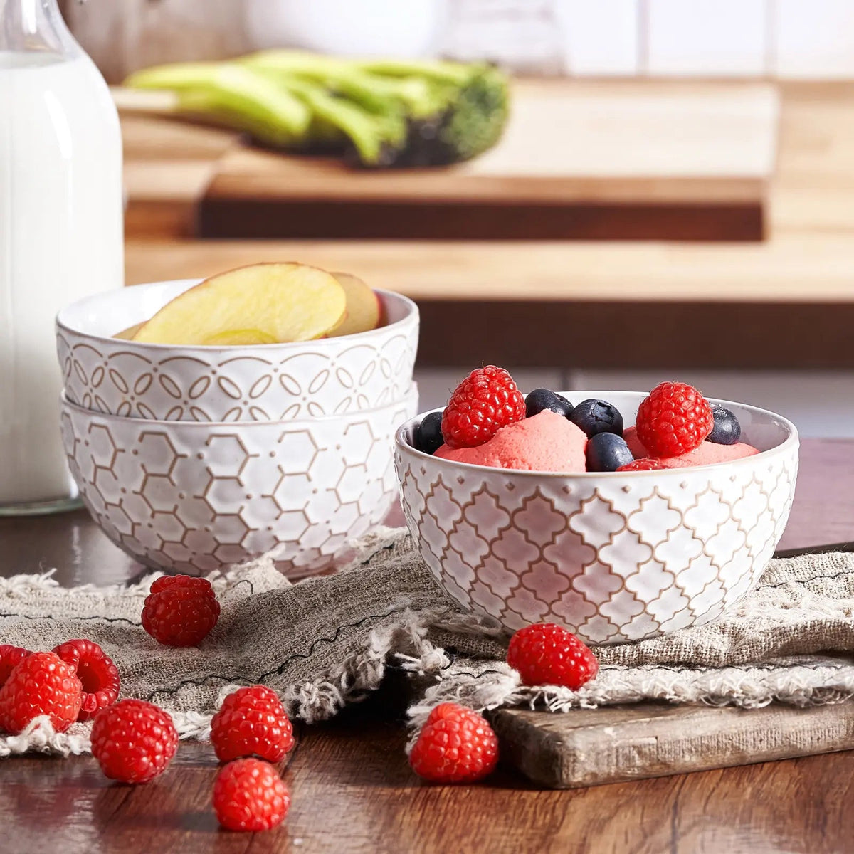 Two patterned ceramic bowls with fruit on a wooden surface