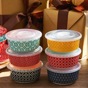 Stacked food containers with patterned lids in front of wrapped gifts.