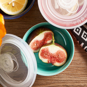 Sliced figs in a teal bowl with a lid on a wooden surface