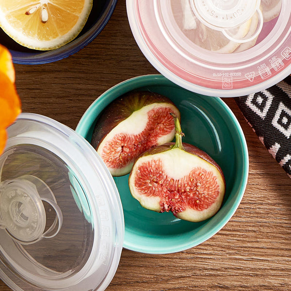 Sliced figs in a teal bowl with a lid on a wooden surface