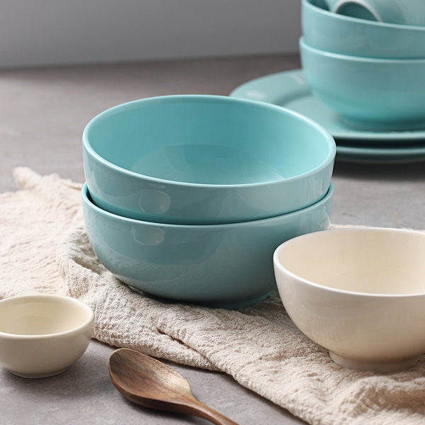 Stacked blue bowls on a textured surface with a wooden spoon.