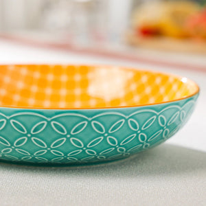 Ceramic bowl with orange top and teal bottom featuring a geometric pattern on a light surface.