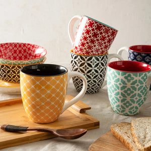 colorful coffe  mugs and bowls on a table with a wooden spoon and bread slices.