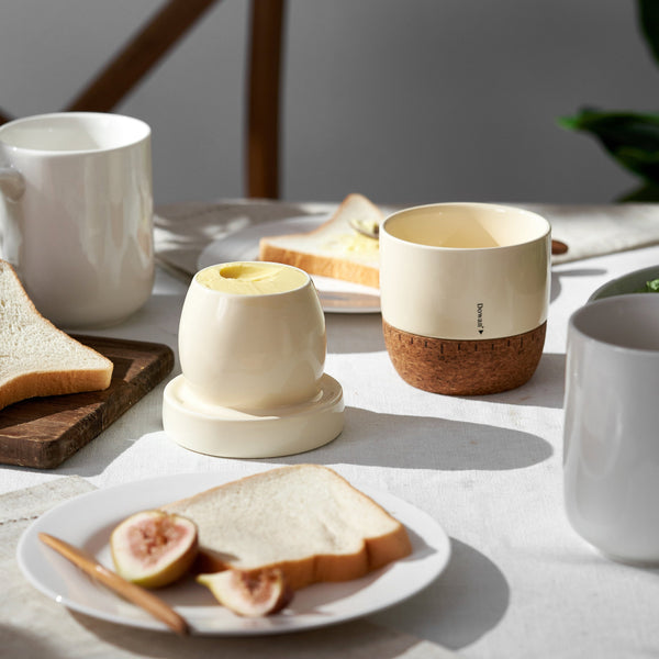 Table setting with ceramic cups, toast, and figs on a light surface.