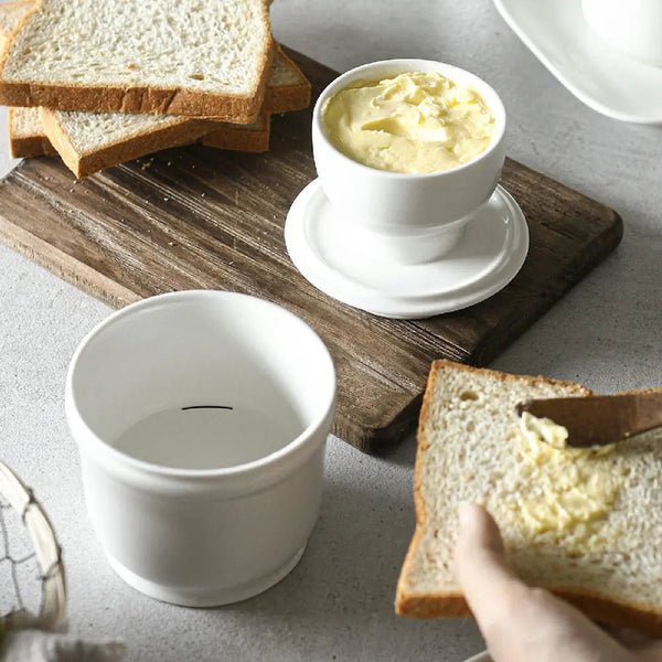 Butter dish with buttered bread on a wooden cutting board
