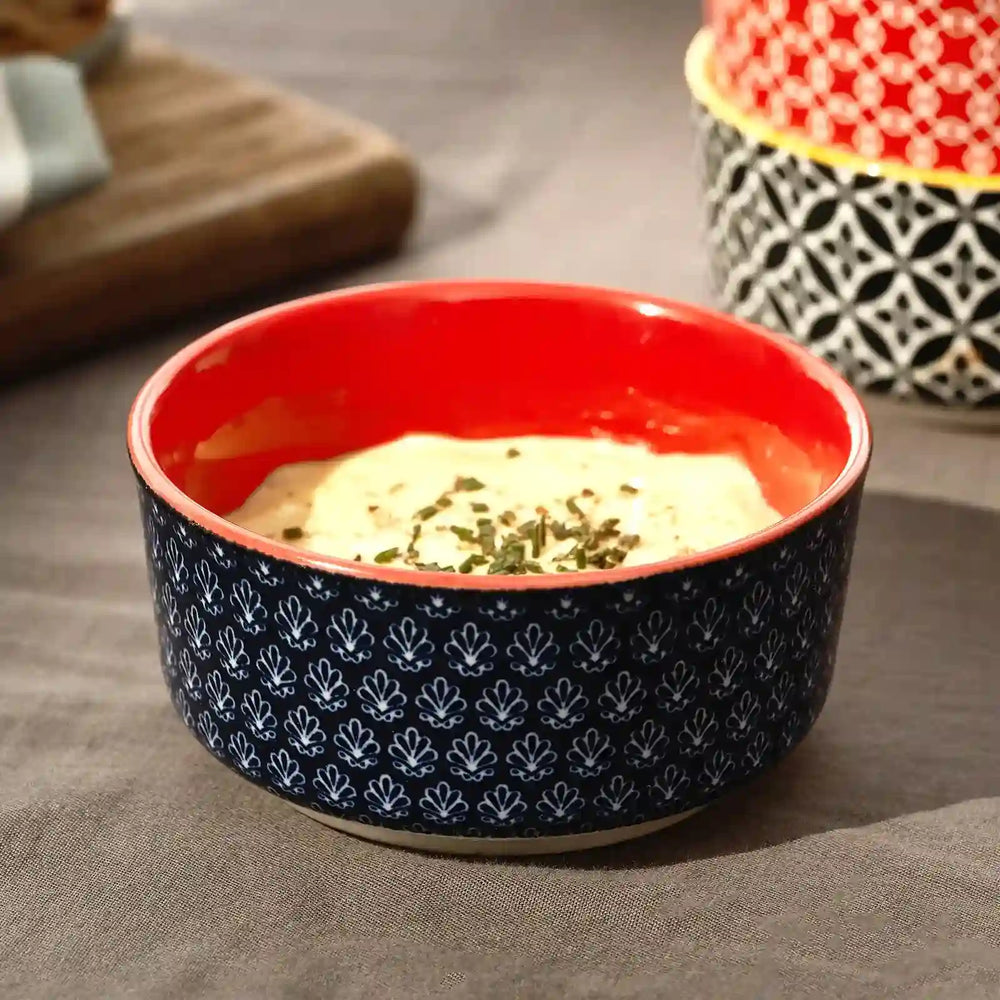 Set of six colorful patterned bowls with lids on a white background