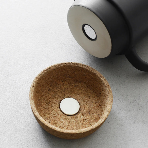 Cork bowl with a white circular object on a light gray surface