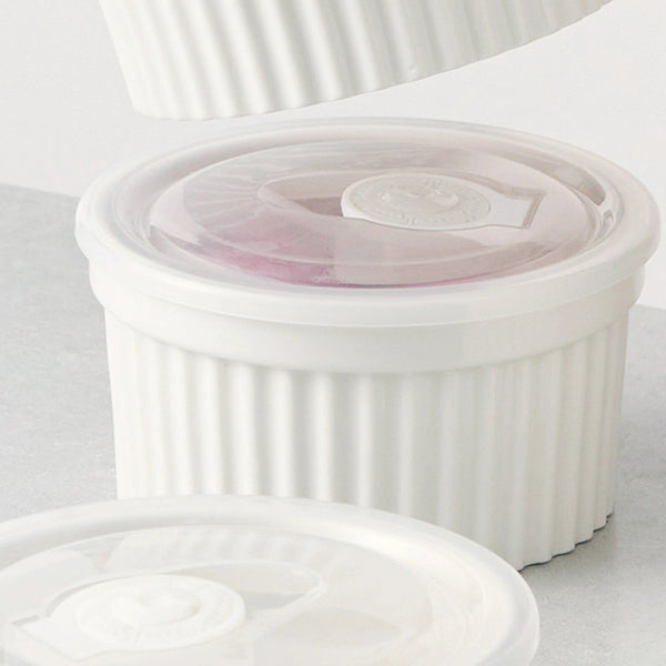 Set of white ceramic ramekins with lids on a light gray background
