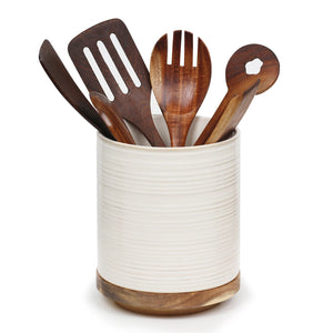 Set of wooden kitchen utensils in a white ceramic holder on a white background