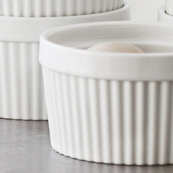 White ceramic ramekins with ribbed texture on a gray surface