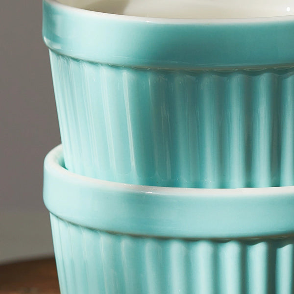 Two stacked turquoise ceramic pots with ribbed texture on a neutral background